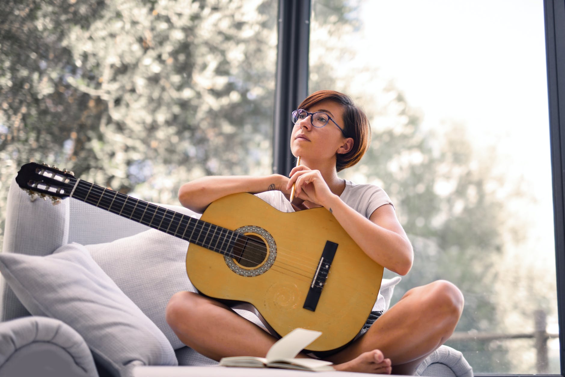 woman in white tank top while holding acoustic guitar